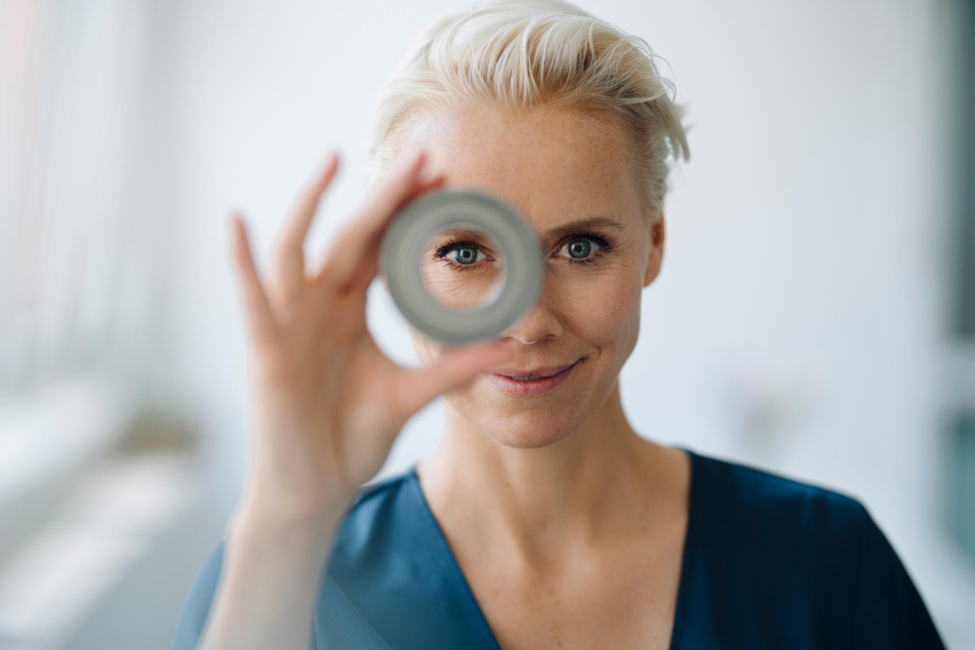 A woman looks attentively through a tube.
